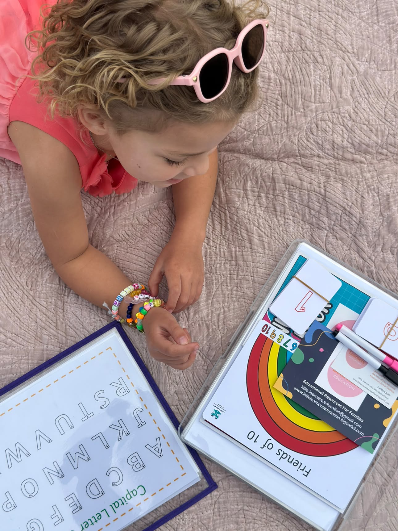 A child exploring Little Learners capital letters and Friends of 10 resources on a blanket